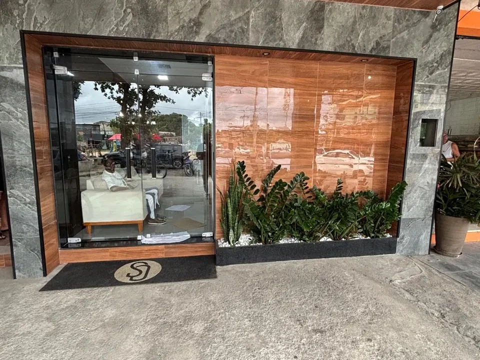 Vitrine envidraçada com revestimento em madeira e jardim na fachada do prédio