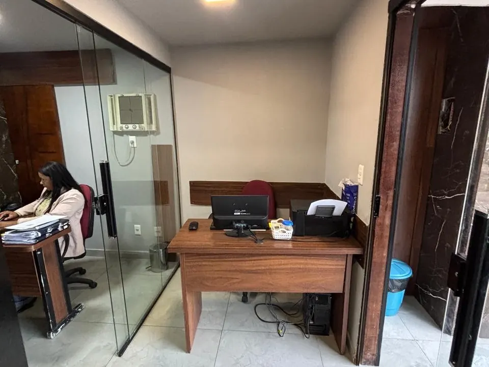 Sala de trabalho do escritório com mesas em madeira e divisórias de vidro